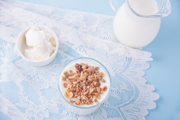 Granola z jogurtem w szkle, mleku i twarogu na niebieskim stole