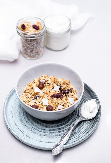 Zdjęcie granola z nasionami chia, suchymi jagodami kokosowymi i jogurtem w miskach na szarym tle