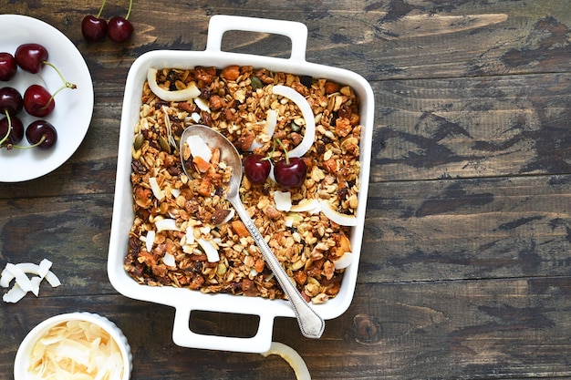 Granola z orzechami kokosowymi i jagodami w naczyniu do pieczenia na drewnianym tle Widok z góry