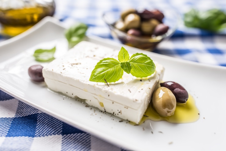 Zdjęcie grecki ser feta z oliwkami i listkami bazylii.