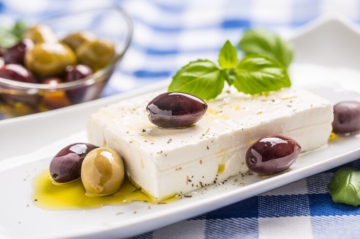 Zdjęcie grecki ser feta z oliwkami i listkami bazylii.