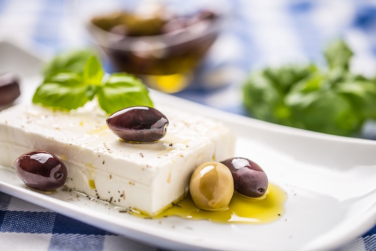 Zdjęcie grecki ser feta z oliwkami i listkami bazylii.