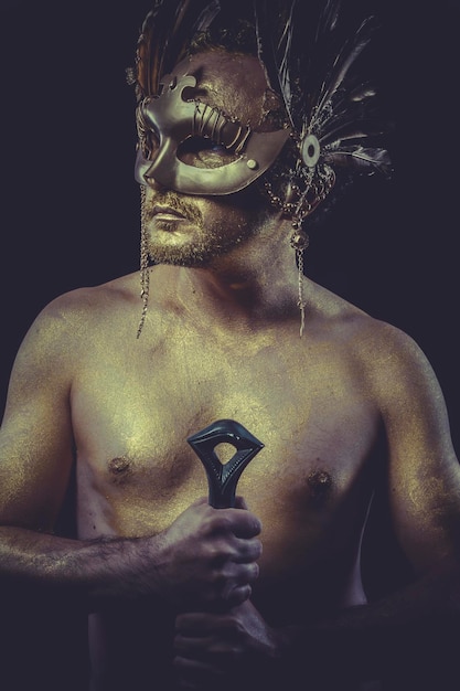 Grek z maską ze złotego pióra na ciele i stalowym mieczem