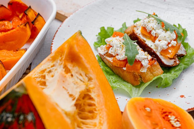 Grillowana bruschetta ciabatta z pieczoną dynią, rukolą z fety i przyprawami. zdrowa jesień pieczona przekąska z dyni