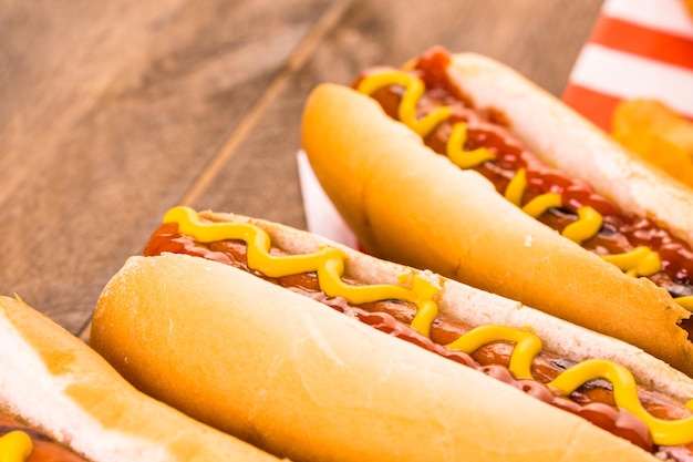 Grillowane hot dogi na bułkach z białym hot dogiem z musztardą i ketchupem.