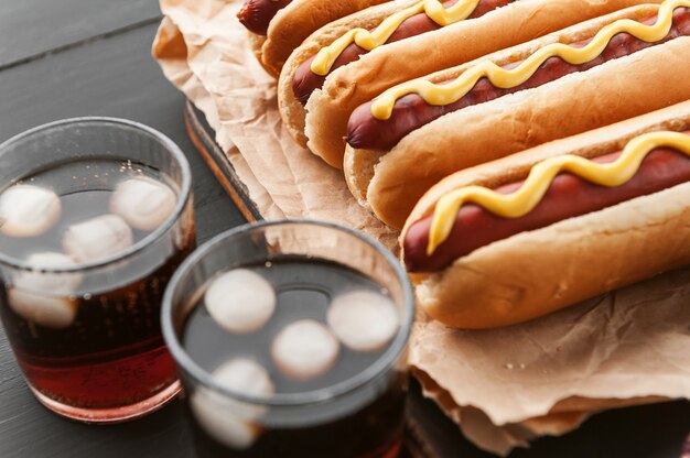 Zdjęcie grillowane hot dogi z grilla z żółtą amerykańską musztardą, na ciemnym drewnianym tle