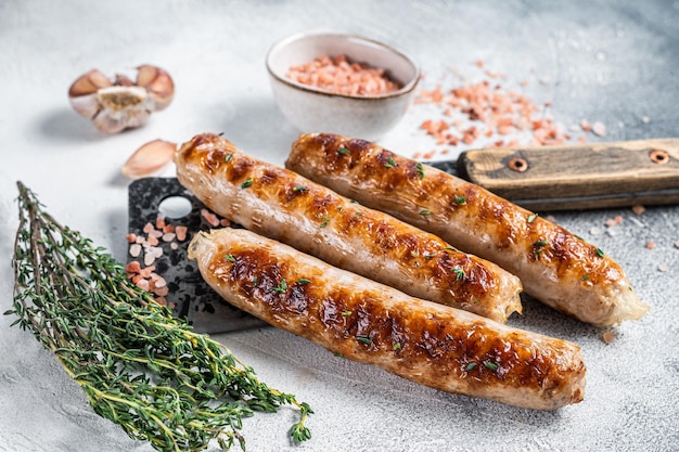 Grillowane kiełbaski mięsne z Bockwurst i Bratwurst na tasaku. Białe tło. Widok z góry.