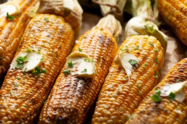 Zdjęcie grillowane kolby kukurydzy słodkiej z masłem przyprawionym korianderem z bliskiego oglądania z niskiego kąta