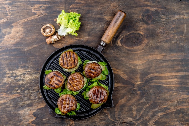 Grillowane portobello bun pieczone hamburgery na żeliwnej patelni grillowej ob drewniane, widok z góry