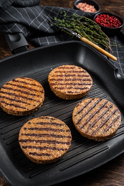 Grillowane wegetariańskie burgery mięsne na bazie roślin wegańskie kotlety na patelni grillowej Drewniane tło Widok z góry