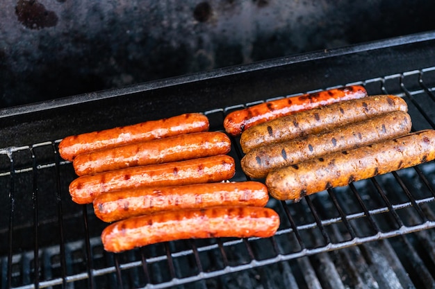 Grillowanie hot-dogów i świeżych warzyw na zewnętrznym grillu gazowym latem.