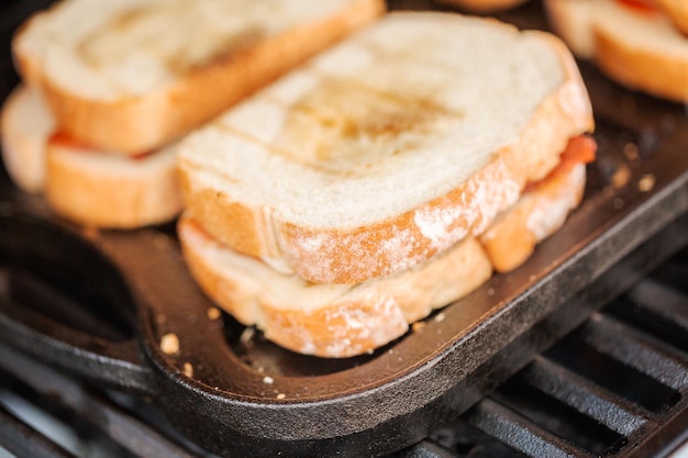 Grillowanie kanapki z serem z grilla z paskami boczku i świeżym pomidorem na grillu gazowym na świeżym powietrzu.