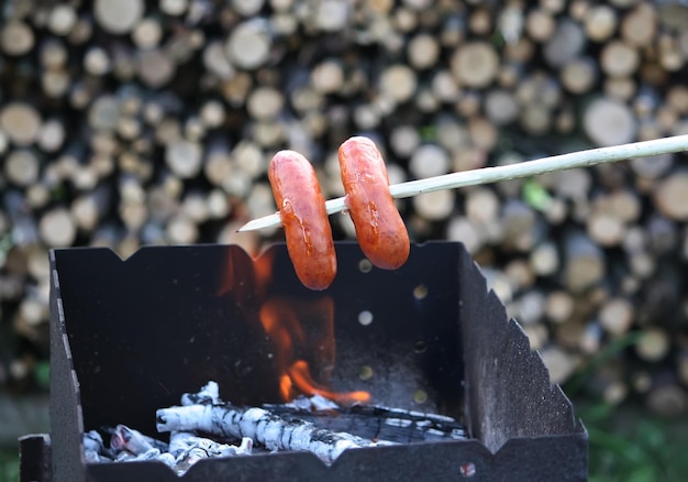 Zdjęcie grillowanie kiełbasek na piknik na świeżym powietrzu nad rusztem