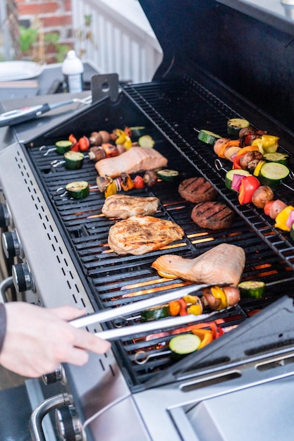 Grillowanie łososia atlantyckiego, piersi z kurczaka, szaszłyków warzywnych i wegetariańskich burgerów na grillu na świeżym powietrzu.