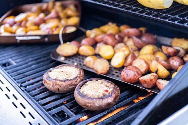 Grillowanie małych ziemniaków z plastrami czosnku na zewnętrznym grillu gazowym.