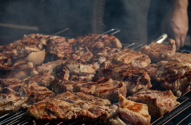 Grillowanie mięsa na zewnątrz. Steki wołowe lub wieprzowe z grilla z dymem. Grill w naturze.