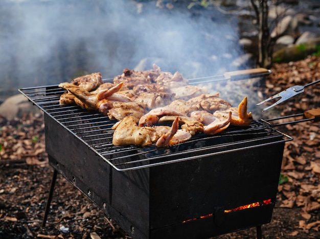 Grillowanie przyprawionego kurczaka w siatce na grillu węglowym. Płytki DOF.