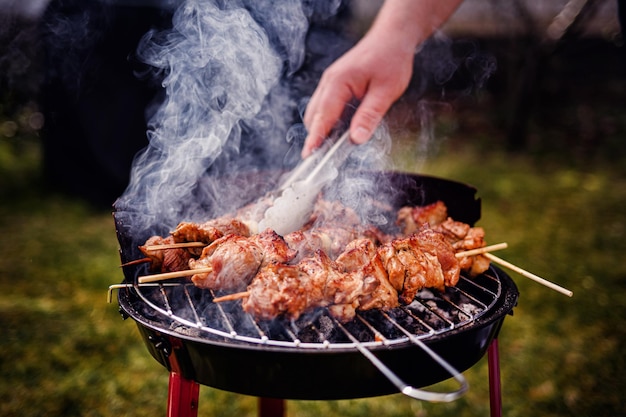 Grillowanie szczypców mięsnych na gorącym węglu na barbecue na świeżym powietrzu