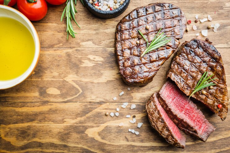 Zdjęcie grillowany stek z mięsa marmurkowego filet mignon z przyprawami. soczysty stek wołowy na deska do krojenia, widok z góry.