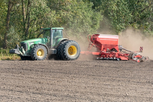 Grodno Białoruś 22 czerwca 2020 Sprzęt siewny pracuje na polu w suchy letni dzień Sezon siewu zbóż Rolnik jadący traktorem z kultywatorem