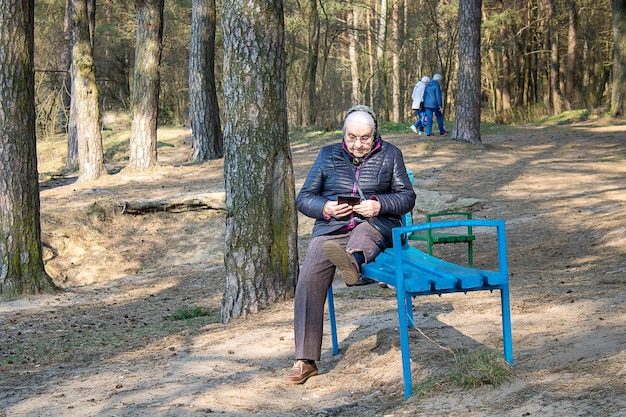 Grodno Białoruś 7 kwietnia 2019 Starsza kobieta w parku czyta ebook