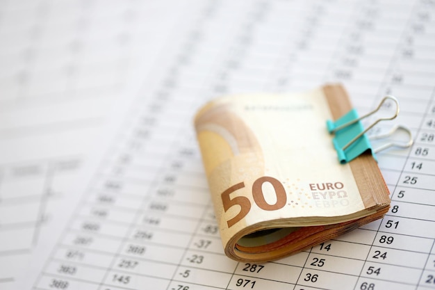 Gromada banknotów euro w spinaczu na papierze z obliczeniami i rachunkami biznesowymi i
