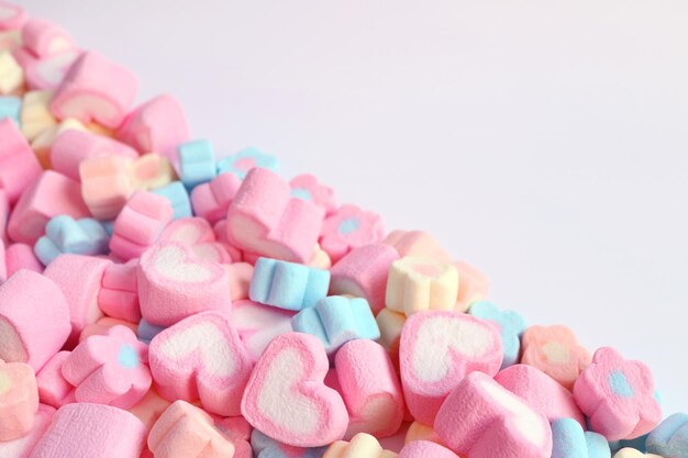 Gromada różowych cukierków w kształcie serca i pastelowych kwiatów w kształcie marshmallow z wolną przestrzenią