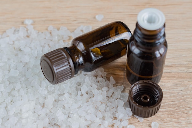 Gromada soli morskiej i butelki z aromatycznym olejem na drewnianym stole Naturalny składnik do spa i peeling