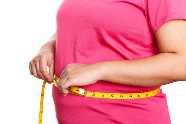 Gruba kobieta mierzy jej żołądek odizolowywający na białym tle