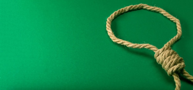 Gruby sznur zawiązany w pętlę na zielonym filcowym stole, uzależniony od hazardu.