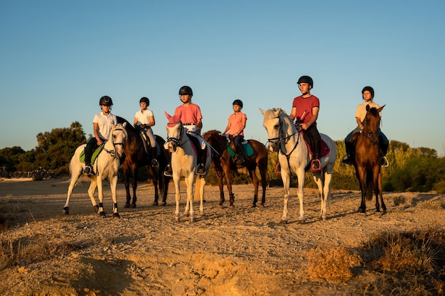Grupa 6 młodych jeźdźców stojących oglądając zachód słońca