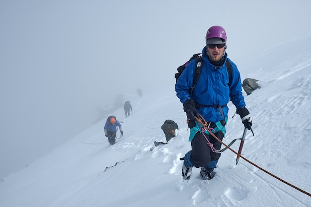 Grupa alpinistów wspina się lub alpinistów na szczyt ośnieżonej góry