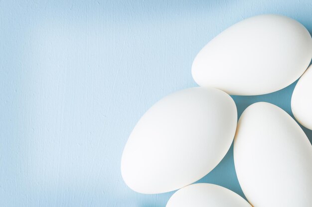 Grupa białych jajek na niebieskim tle tło wielkanocne