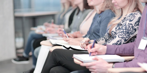Zdjęcie grupa biznesowa robiąca notatki w schowku siedząc w sali konferencyjnej