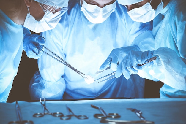 Grupa chirurgów noszących maski ochronne wykonujących operację. Koncepcja medycyny.