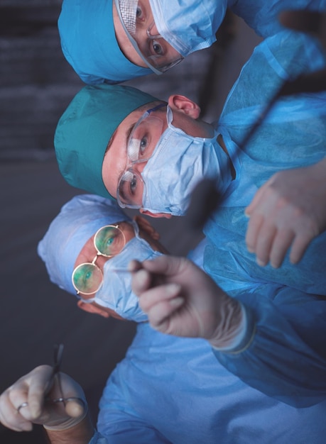 Grupa Chirurgów W Pracy Na Sali Operacyjnej Stonowanych Na Niebiesko Zespół Medyczny Wykonujący Operację