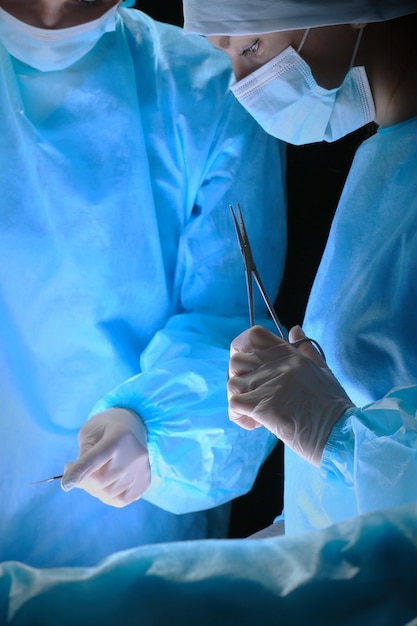 Grupa chirurgów w pracy na sali operacyjnej w odcieniach niebieskiego. Zespół medyczny wykonujący operację