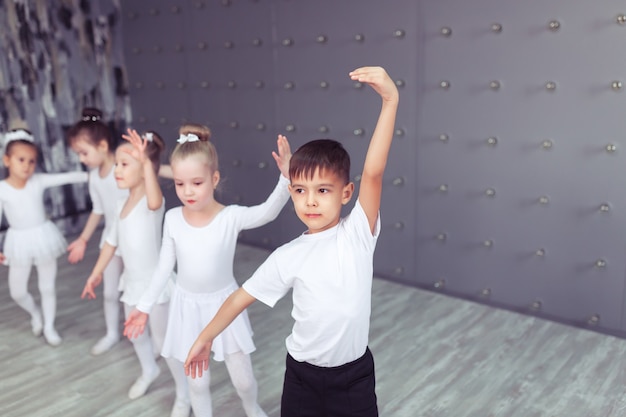 Grupa czterech małych baletnic i dziecięcej baleriny pozują razem i ćwiczą