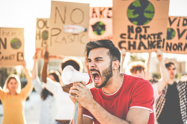 Zdjęcie grupa demonstrujących milenialsów na drodze, młodzi ludzie z różnych kultur i ras walczą o zanieczyszczenie tworzywem sztucznym i zmianę klimatu - koncepcja globalnego ocieplenia i środowiska - koncentracja na twarzy mężczyzny