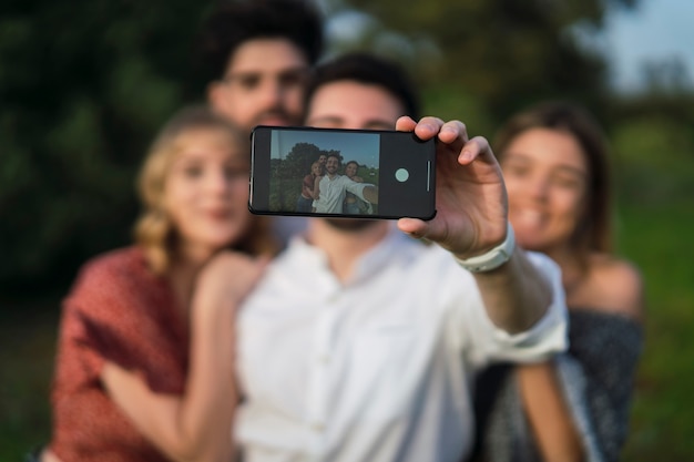 Grupa dwóch chłopców i dwóch dziewczyn robiących selfie ze smartfonem