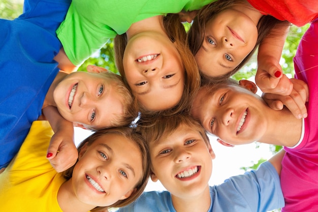 Zdjęcie grupa dzieci stojących w kręgu i przytulających się, widok z dołu
