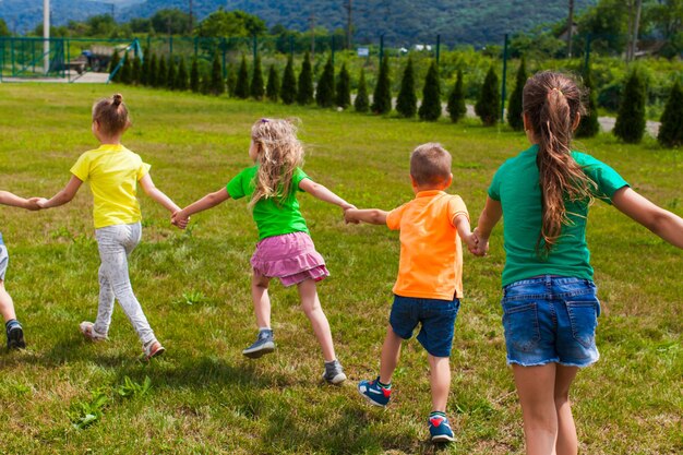 Grupa dzieci w kolorowych koszulkach bawiących się i biegających podczas letnich wakacji