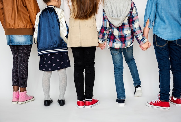 Zdjęcie grupa dzieciaki trzyma ręki za tylni widokiem na białym blackground