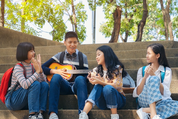 Grupa dziecko uczeń bawić się gitarę i śpiewa piosenki wpólnie w lato parku