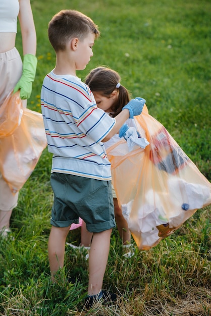 Zdjęcie grupa dziewcząt z dziećmi o zachodzie słońca zajmuje się wywozem śmieci w parku. troska o środowisko, recykling.