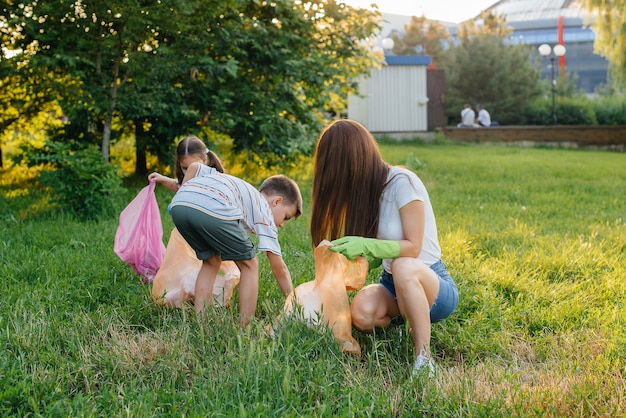 Grupa dziewczyn z dziećmi o zachodzie słońca zajmuje się wywozem śmieci w parku. Troska o środowisko, recykling.