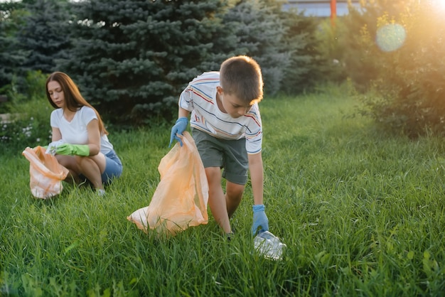 Grupa dziewczyn z dziećmi o zachodzie słońca zajmuje się wywozem śmieci w parku. Troska o środowisko, recykling.