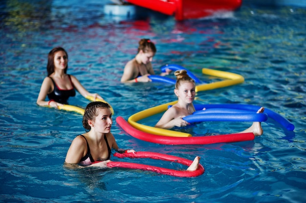 Grupa fitness dziewcząt robi ćwiczenia aerobowe w basenie w parku wodnym.