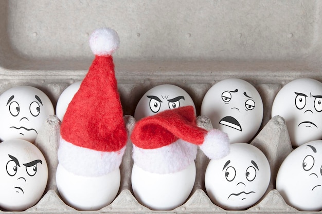 Grupa jaj w zabawkowych czapkach świątecznych z rysowanymi emocjami