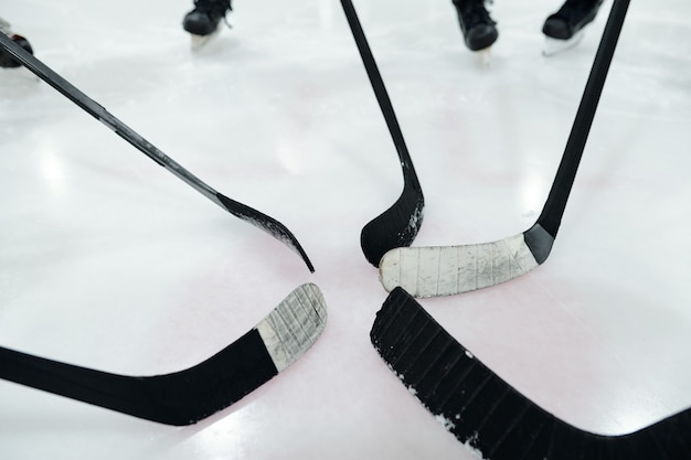 Zdjęcie grupa kijów hokejowych w środku koła złożona z kilku zawodników stojących na lodowisku i trenujących podczas przygotowań do gry